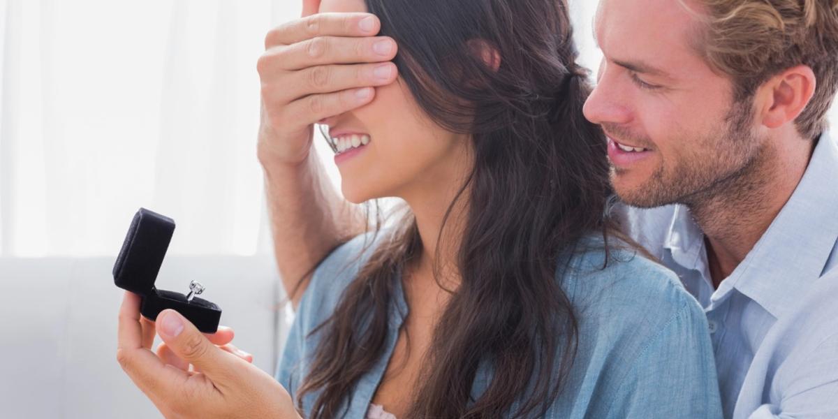 Man hiding his girlfriend's eyes to offer her an engagement ring.