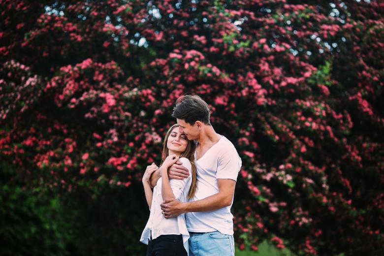 couple embracing in front of blooming tree
